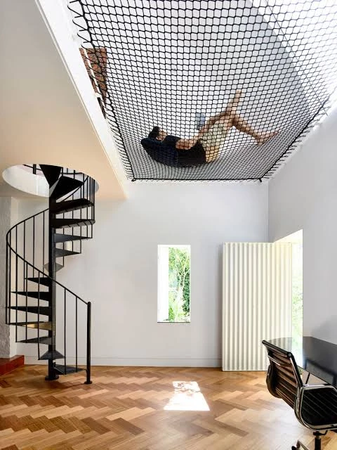 Design reference showing a person reclining on an indoor loft hammock net